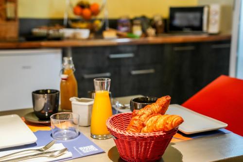 a table with a basket of croissants and orange juice at Logis Hôtel & Restaurant Le Cadet de Gascogne in Saint-Justin