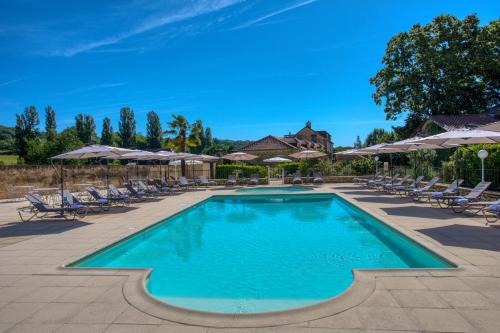 a swimming pool with chairs and umbrellas at Domaine de Monrecour - Hôtel & Restaurant - Proche de Sarlat in Saint-Vincent-de-Cosse