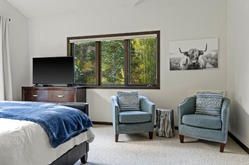a bedroom with a bed and two chairs and a television at 4501 Spruce Way in Mid Vail