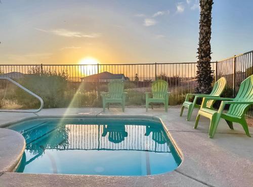 a swimming pool with chairs and a sunset in the background at North Shore Inn at Lake Mead in Moapa Valley