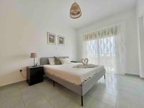 a white bedroom with a bed and a window at Niove Budget One-Bedroom Apartment in Paralimni