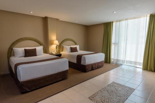 a hotel room with two beds and a large window at Gamma Cuernavaca Puerta Paraiso in Cuernavaca