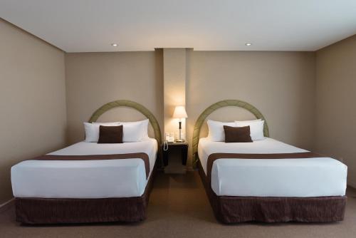 two beds in a hotel room with two beds at Gamma Cuernavaca Puerta Paraiso in Cuernavaca