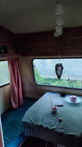 a room with a table and a heart hanging from a window at Kisoroszi Szigetcsúcs Lakókocsi-Vissza a természetbe a Duna parton in Kisoroszi