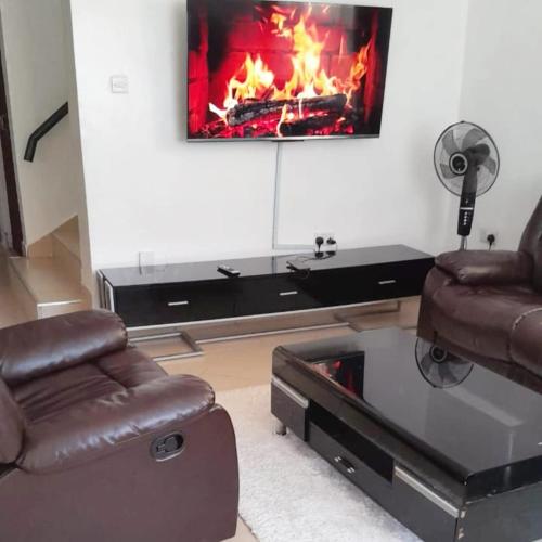 a living room with two chairs and a fireplace at Sofitel Executive 4 bedrooms Milimani in Kisumu