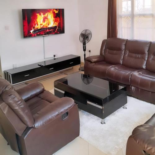 a living room with two leather couches and a fireplace at Sofitel Executive 4 bedrooms Milimani in Kisumu