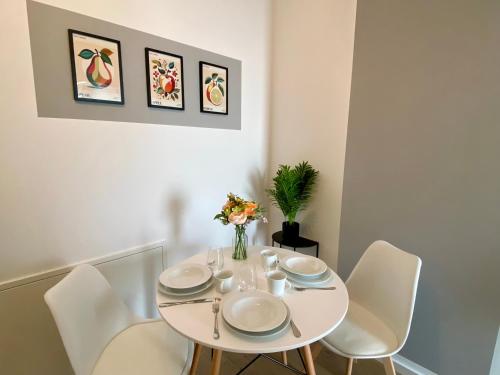 a white dining room table with white chairs and a vase of flowers at Apartments am Lutherplatz in Potsdam