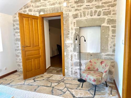 a bedroom with a stone wall and a chair in front of a door at Villa Sveti Stefan in Budva