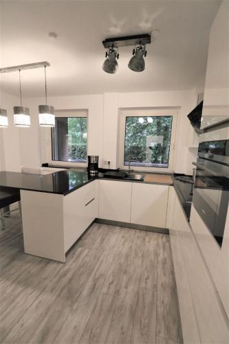 a kitchen with white cabinets and black counter tops at Riverside: Messe-, Business-, Ferienwohnung in Leichlingen