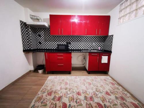 une cuisine rouge avec des armoires rouges et un tapis dans l'établissement Centre-ville Sevran f3, à Sevran