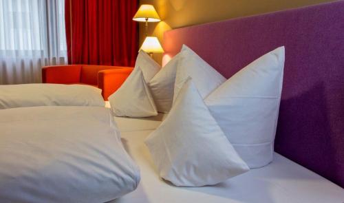 a hotel room with white pillows on a bed at Schurwald Hotel in Plochingen
