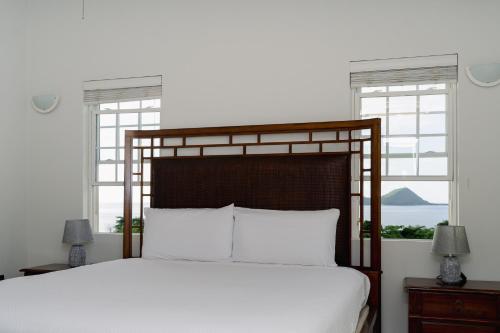 ein Schlafzimmer mit einem Bett mit weißen Laken und Fenstern in der Unterkunft Tibay Villas in Portsmouth