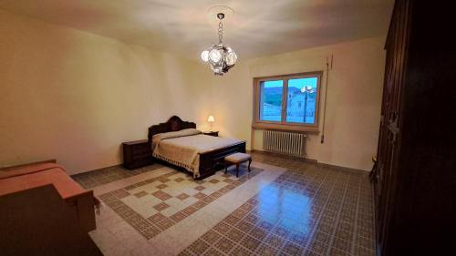 a bedroom with a bed and a window and a chandelier at Casa Vacanze Taranta in Taranta Peligna