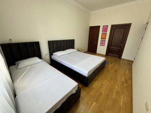 two beds in a room with wooden floors at Velvet Vouge Hostel in Yerevan