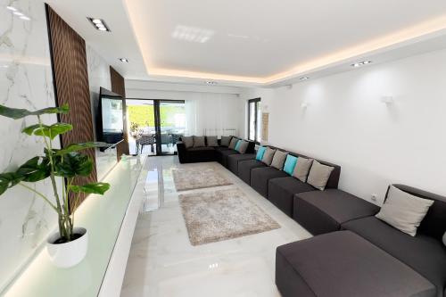 a living room with black couches and a couch at Villa Ring Pool & Padel Belgrade in Barič