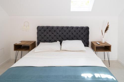 a bed with a black headboard and two tables at Villa Ring Pool & Padel Belgrade in Barič