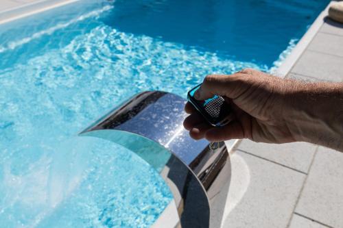 a person holding a cell phone in front of a swimming pool at Villa Ring Pool & Padel Belgrade in Barič