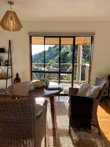 a living room with a table and chairs and a large window at Fern Cottage Escape in Nelson