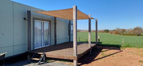 a house with a wooden deck with a canopy at La Demorada, cómoda casa en entorno natural in Mercedes