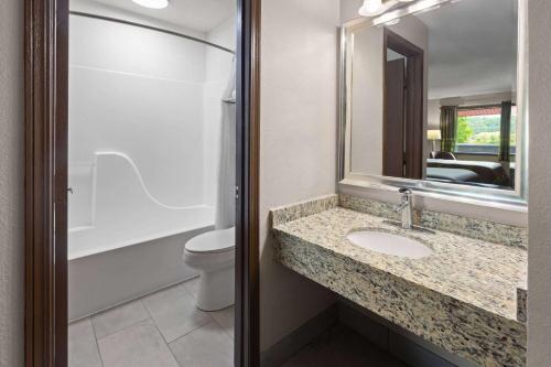 a bathroom with a sink and a toilet and a mirror at Super 8 by Wyndham Bridgeport/Clarksburg Area in Bridgeport