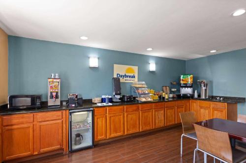 a kitchen with wooden cabinets and a blue wall at Days Inn by Wyndham Glasgow in Glasgow