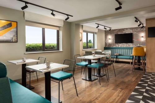 a restaurant with tables and chairs and a couch at Super 8 by Wyndham Durham in Durham