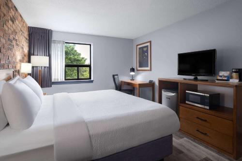 a hotel room with a bed and a flat screen tv at Travelodge by Wyndham Barrie in Barrie