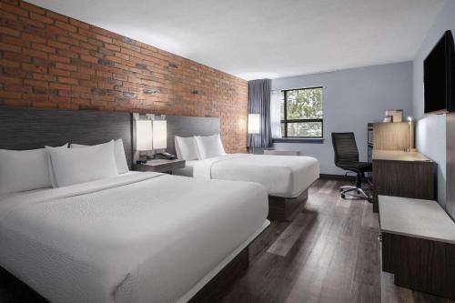 a hotel room with two beds and a desk at Travelodge by Wyndham Barrie in Barrie