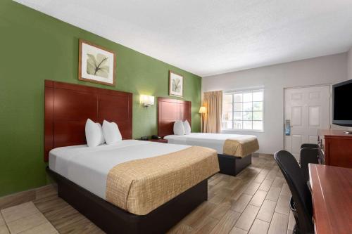 a hotel room with two beds and a flat screen tv at Travelodge Suites by Wyndham Lake Okeechobee in Okeechobee
