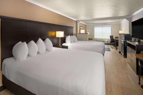 a hotel room with two beds and a desk at Ramada by Wyndham Moses Lake in Moses Lake