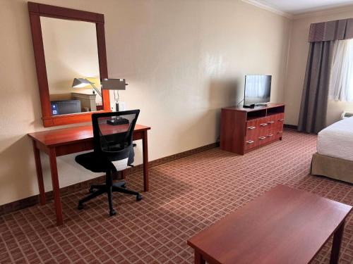 a hotel room with a desk and a bed and a mirror at Ramada by Wyndham College Station in College Station