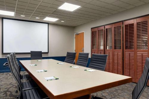 a conference room with a table and chairs and a whiteboard at Wingate by Wyndham Louisville East in Louisville