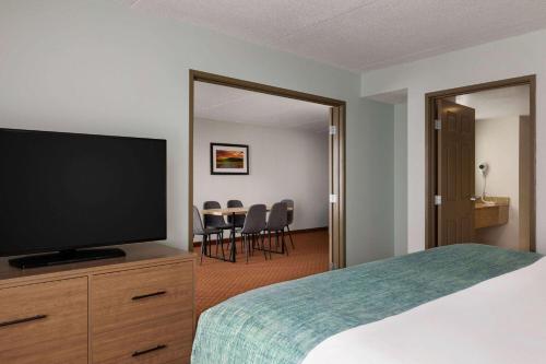 a hotel room with a bed and a flat screen tv at Wingate by Wyndham Louisville East in Louisville