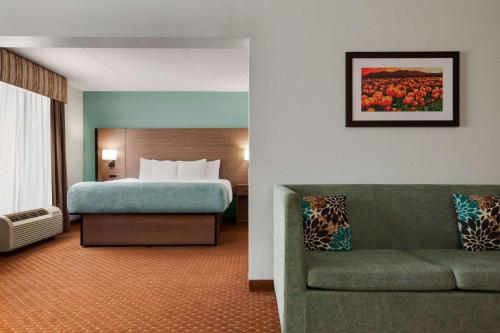 a hotel room with a bed and a couch at Wingate by Wyndham Louisville East in Louisville