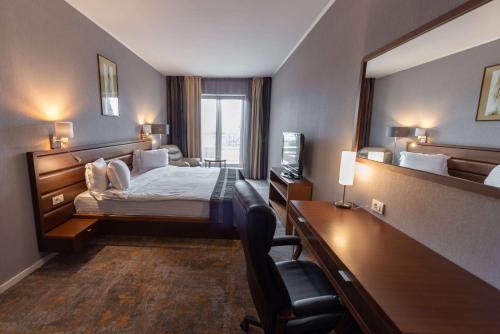 a hotel room with a bed and a desk with a computer at Wyndham Cluj in Cluj-Napoca