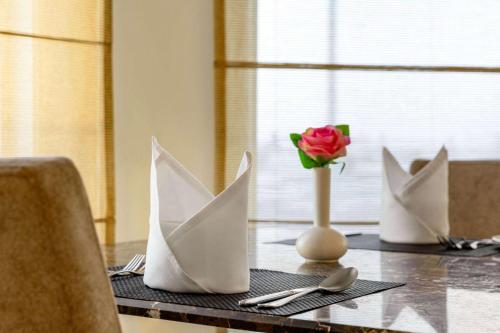 a table with a vase with a rose in it at Grand Regency Doha, Trademark Collection by Wyndham in Doha