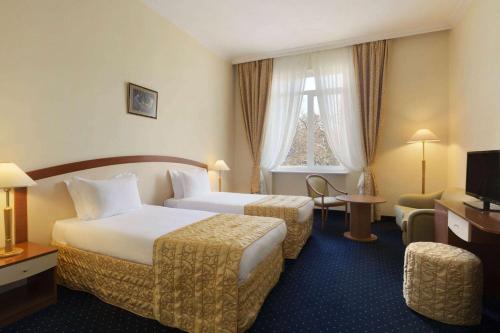 a hotel room with two beds and a window at Ramada by Wyndham Plovdiv Trimontium in Plovdiv