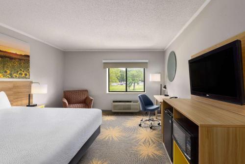 a hotel room with a bed and a flat screen tv at Days Inn & Suites by Wyndham Kansas City - CHIEFS Stadium in Kansas City