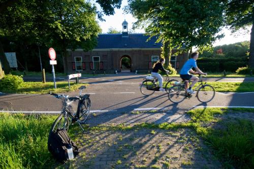 two people riding bikes on a road in front of a building at Hotel / Pension Villa Tanahlot in Zandvoort