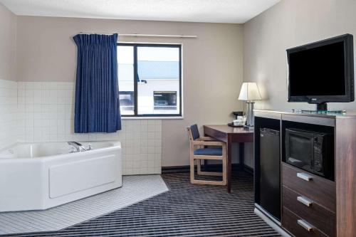 a hotel room with a tub and a tv and a desk at Super 8 by Wyndham Humboldt in Humboldt