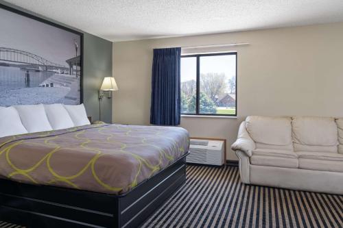 a hotel room with a bed and a couch and a window at Super 8 by Wyndham Humboldt in Humboldt