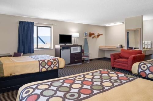 a hotel room with two beds and a chair at Super 8 by Wyndham Humboldt in Humboldt