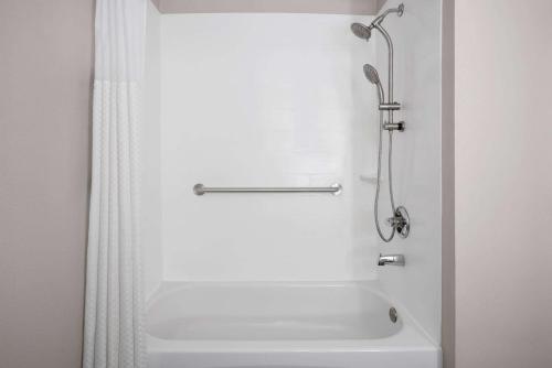 a bathroom with a shower and a white tub at Microtel Inn by Wyndham Raleigh-Durham Airport in Morrisville