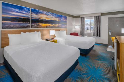 a hotel room with two beds and a desk at Days Inn by Wyndham Delta CO in Delta