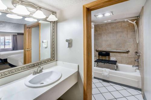 a bathroom with a sink and a mirror and a tub at Days Inn by Wyndham Delta CO in Delta
