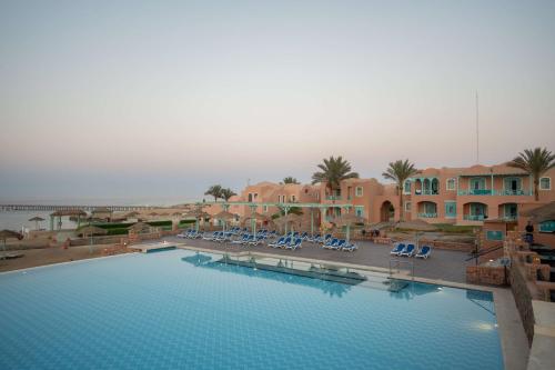 a large swimming pool with blue chairs and buildings at Radisson Blu Resort El Quseir in Quseir