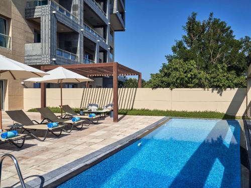 a swimming pool with chairs and umbrellas next to a building at Rixos The Palm Hotel & Suites - Ultra All Inclusive in Dubai