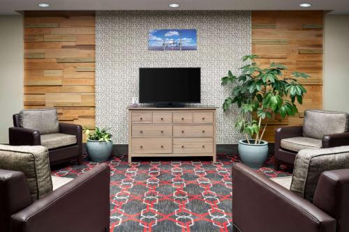 a waiting room with a flat screen tv and chairs at Wyndham Garden Inn Pittsburgh Airport in Robinson Township