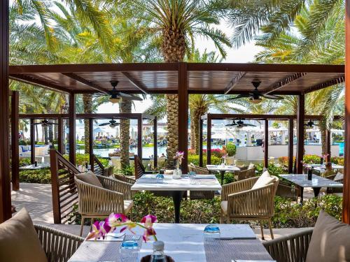a restaurant with tables and chairs and palm trees at Rixos The Palm Hotel & Suites - Ultra All Inclusive in Dubai