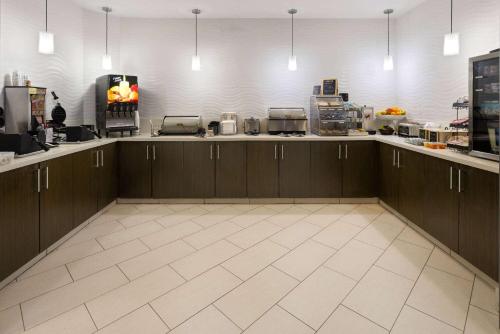 een keuken met bruine kasten en een witte tegelvloer bij La Quinta by Wyndham Kokomo in Kokomo